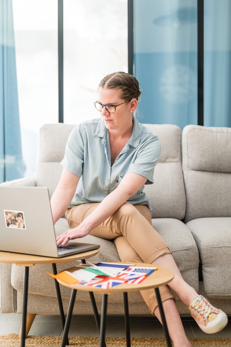 philippine-sikora-redactrice-web-seo-bilingue Philippine SIKORA tapant à l'ordinateur. Les drapeaux de l'Irlande, de la France, du UK et des US à côté d'elle.