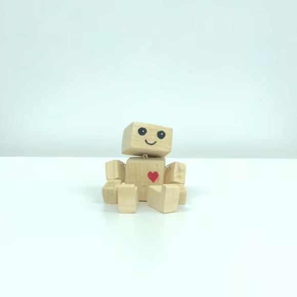 Un robot en bois est assis et souriant. Un cœur rouge est peint sur sa poitrine.